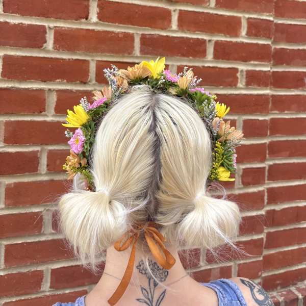 Flower crown on a blonde person with pink and yellow blooms