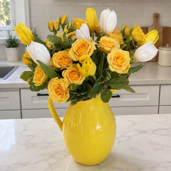 Yellow and white tulips with yellow roses in a yellow pitcher vase