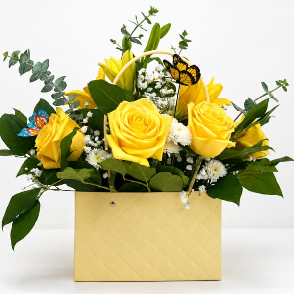 Yellow roses and white filler flowers in a pale yellow box with butterfly picks