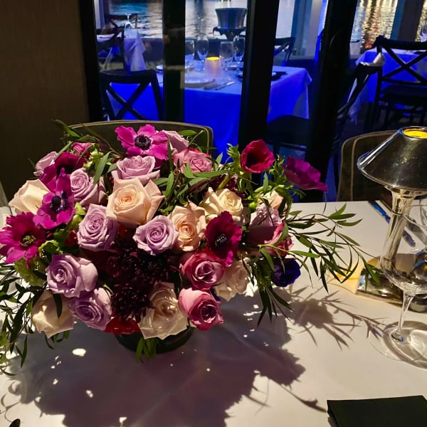 Low centerpiece of pink and lavender roses on a dining table