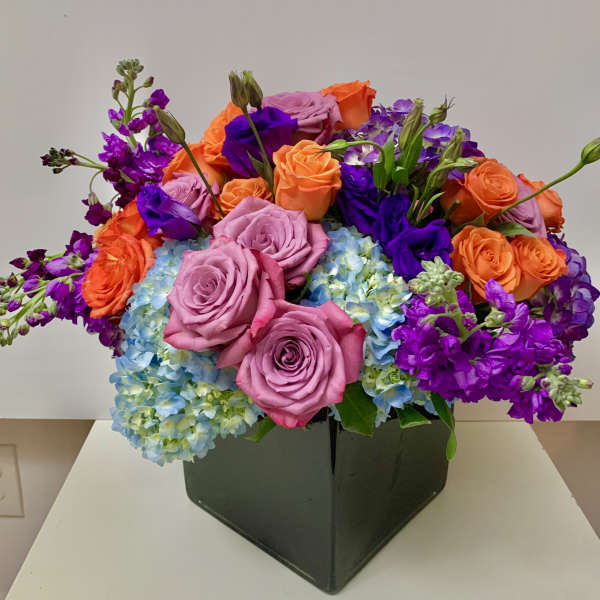 Colorful bouquet of roses, hydrangeas, and purple blooms in a black box