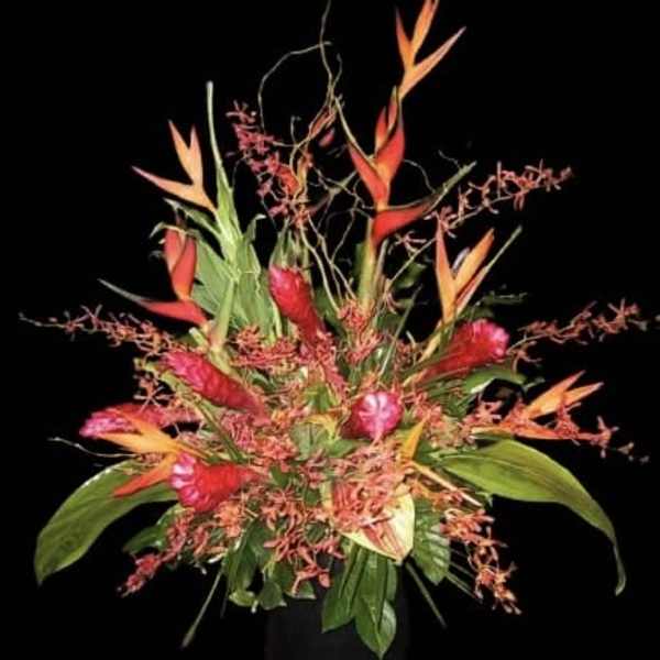 Tropical flower arrangement with red and orange blooms in a vase