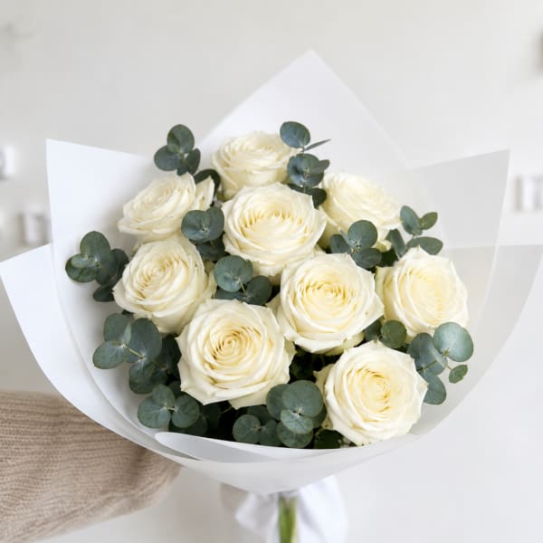 Bouquet of white roses with eucalyptus in white paper wrap