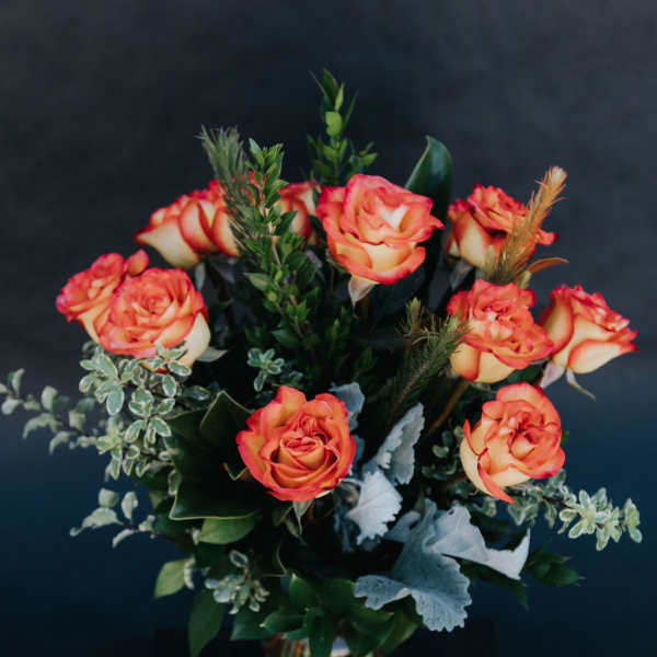 Orange and cream roses arranged in a glass vase