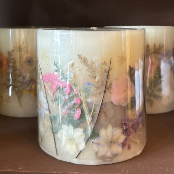 Decorative candle in a clear glass jar with pressed flowers