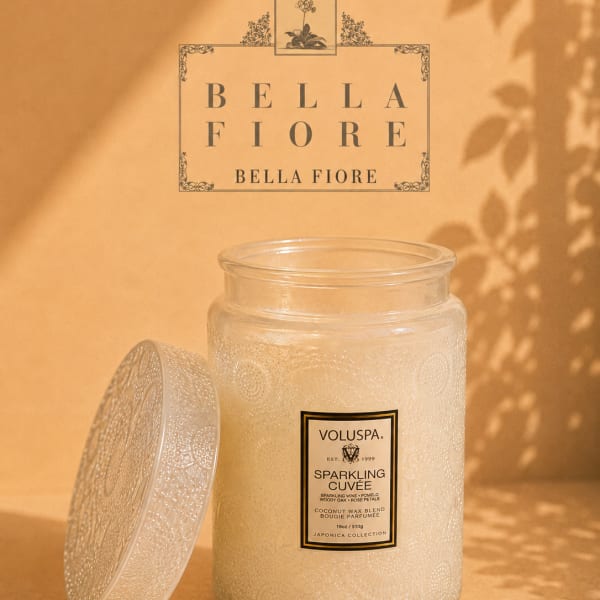 Glass jar candle with a decorative lid on a warm beige background