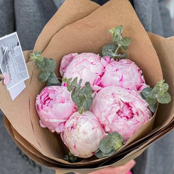 Bouquet of pale pink peonies wrapped in brown paper