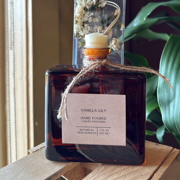 Amber reed diffuser bottle labeled Vanilla Lily with dried flowers