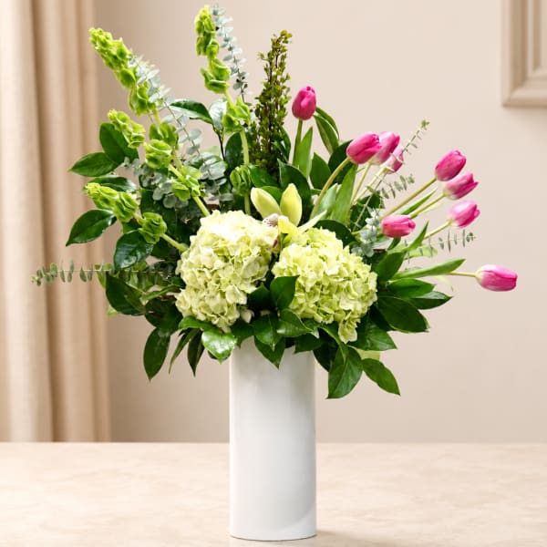 Pink tulips and pale green hydrangeas in a white vase