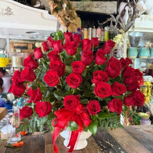Large bouquet of red roses in a white vase with a red ribbon