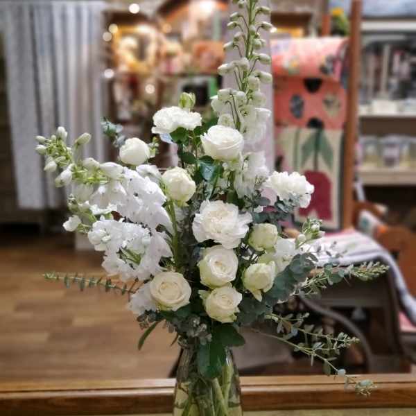 Tall white floral arrangement in a clear glass vase