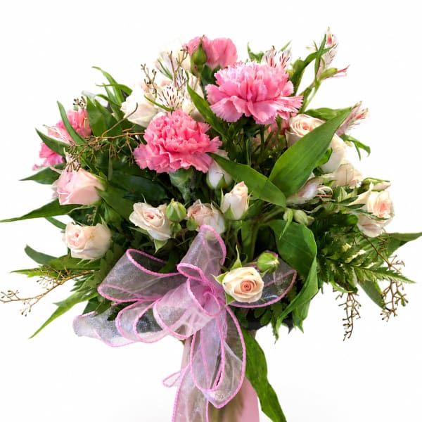 Pink carnations and pale roses in a glass vase with a pink ribbon