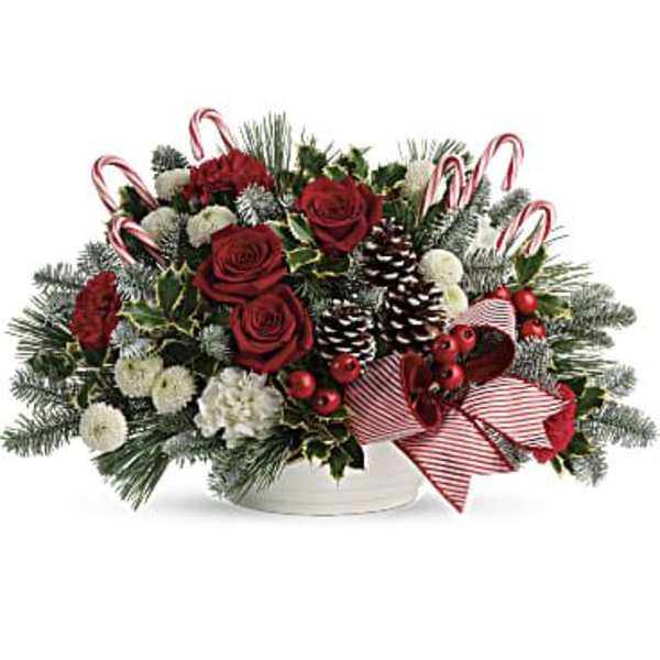 Holiday floral arrangement with red roses, candy canes, and pinecones in a white bowl