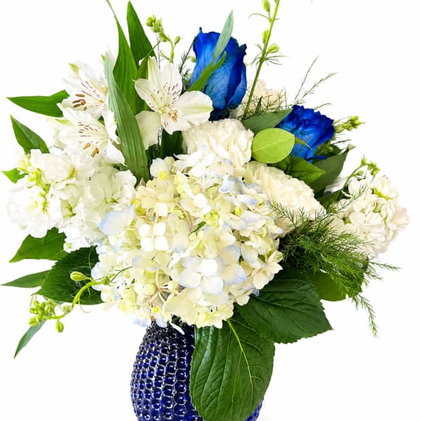 White and blue floral arrangement in a cobalt blue vase