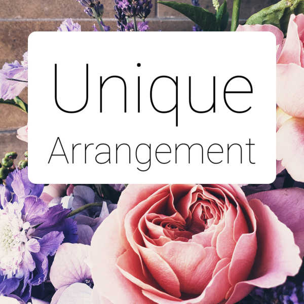 Pink rose and purple flowers behind a sign reading Unique Arrangement