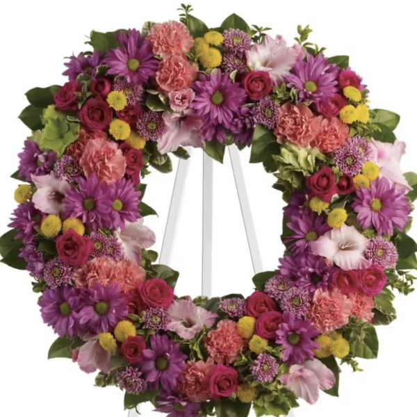 Heart-shaped floral wreath on a white easel with pink, purple, and yellow flowers