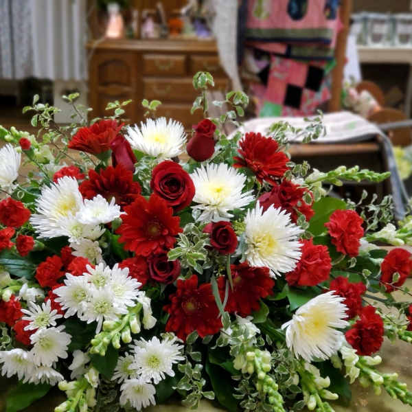 Low floral arrangement of red and white flowers with greenery