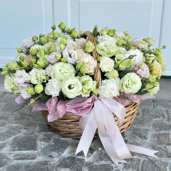 Basket of pale pink and white flowers with a ribbon bow