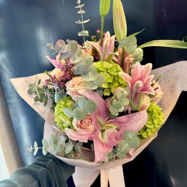 Bouquet of pink lilies, roses, and green hydrangeas wrapped in paper