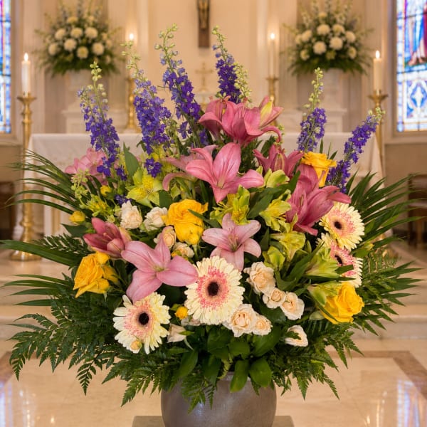 Large mixed floral arrangement in a gray vase with pink lilies and yellow roses