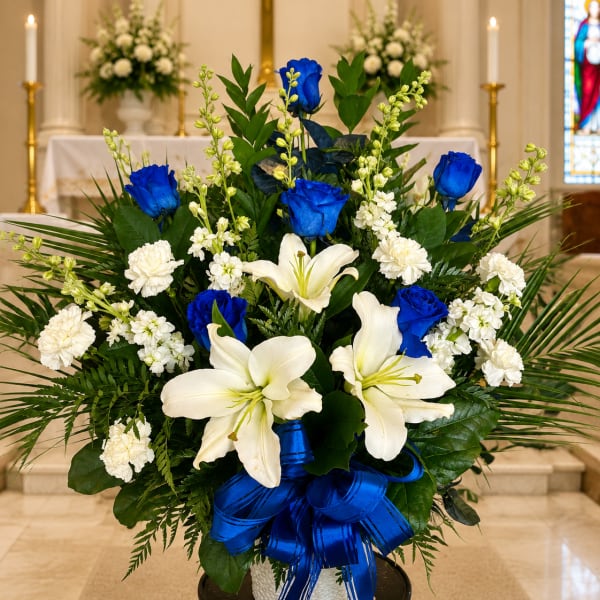White lilies and blue roses in a vase with a blue ribbon