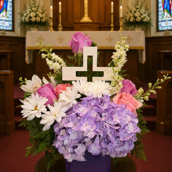 Pastel floral arrangement with a white cross in a purple vase
