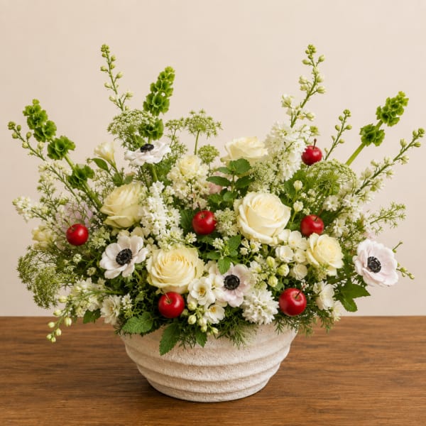 Cream roses and white anemones in a textured white bowl with red berries