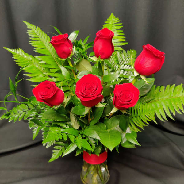 Bouquet of red roses with fern foliage in a clear glass vase