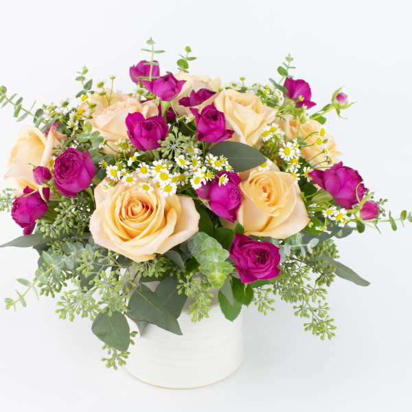 Bouquet of peach and magenta roses in a white vase
