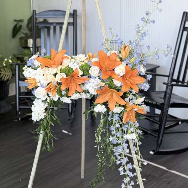 Orange lilies and white flowers arranged on a standing easel