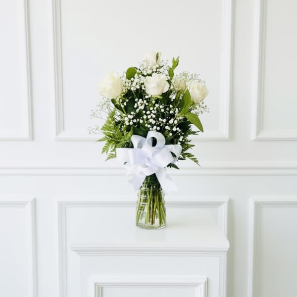 White rose bouquet in a glass vase with a white ribbon