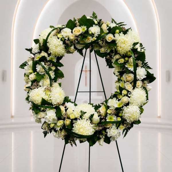 White floral wreath on a stand in a church interior
