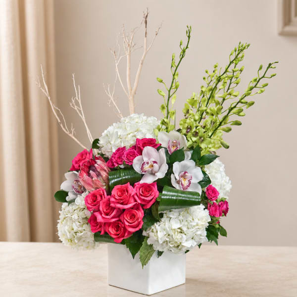 Pink roses, white hydrangeas, and orchids in a white vase
