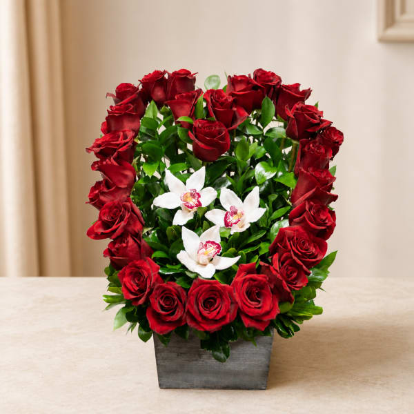 Red roses arranged around white orchids in a square gray vase