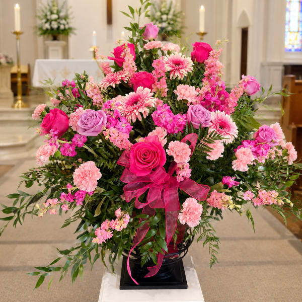 Large pink and lavender floral arrangement in a church setting