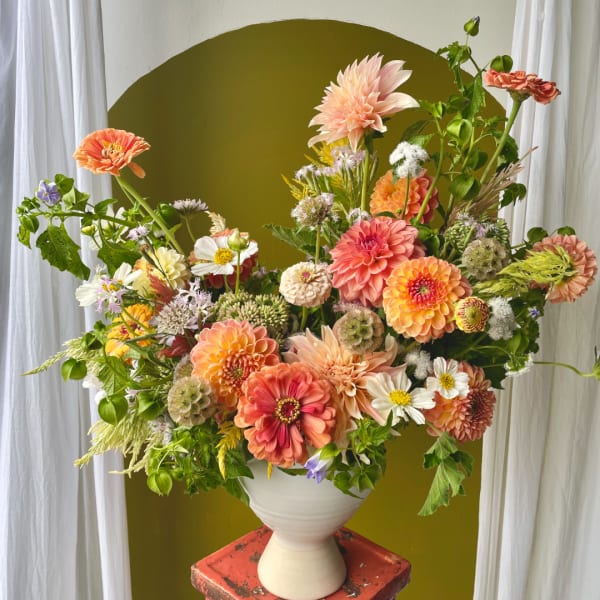 Large mixed bouquet of peach, coral, and white flowers in a white vase