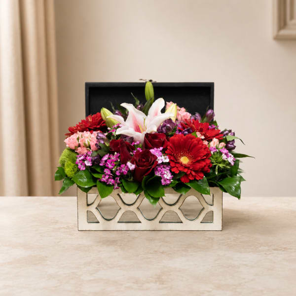 Mixed flower arrangement in a decorative rectangular box with lilies and roses