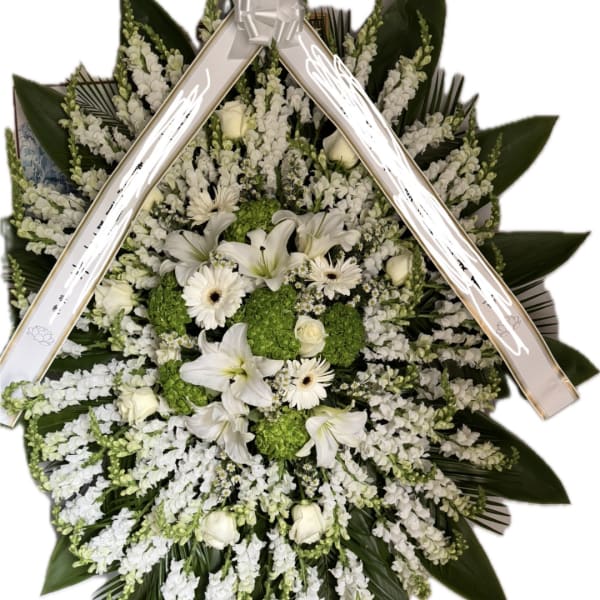 White floral standing spray with lilies, daisies, and green hydrangeas