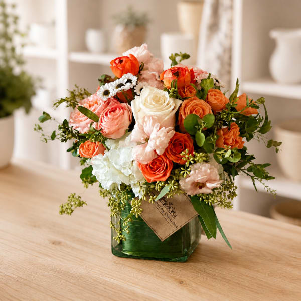 Bouquet of orange, pink, and white flowers in a green glass vase