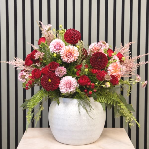 Mixed red and pink flower arrangement in a white vase