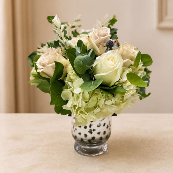 White roses and hydrangeas in a spotted glass vase