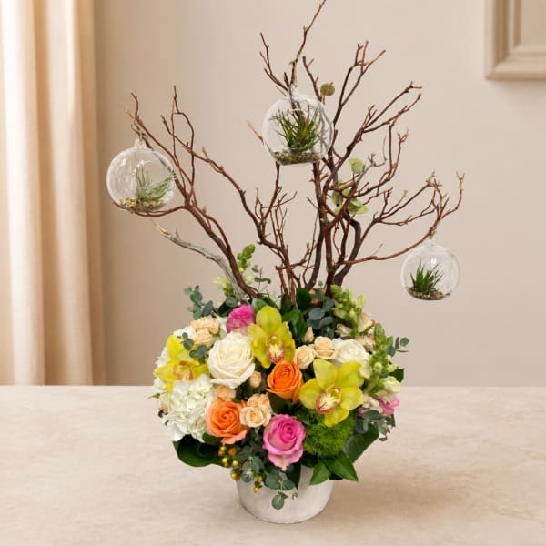 Mixed flower arrangement in a white container with hanging glass terrariums