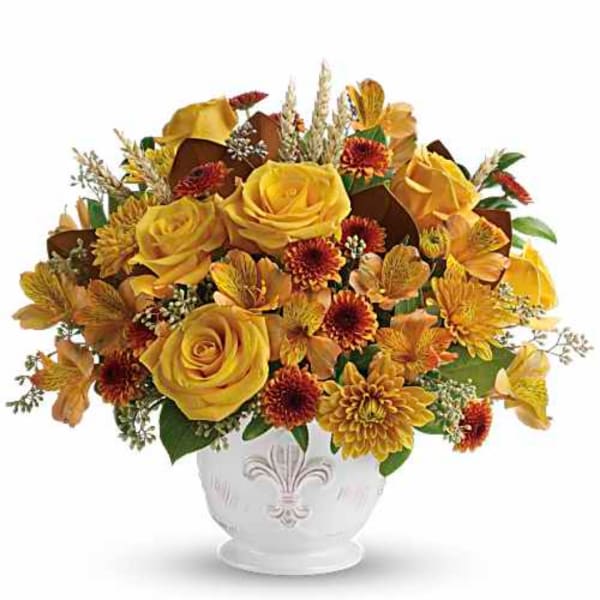 Yellow roses and autumn flowers arranged in a white vase