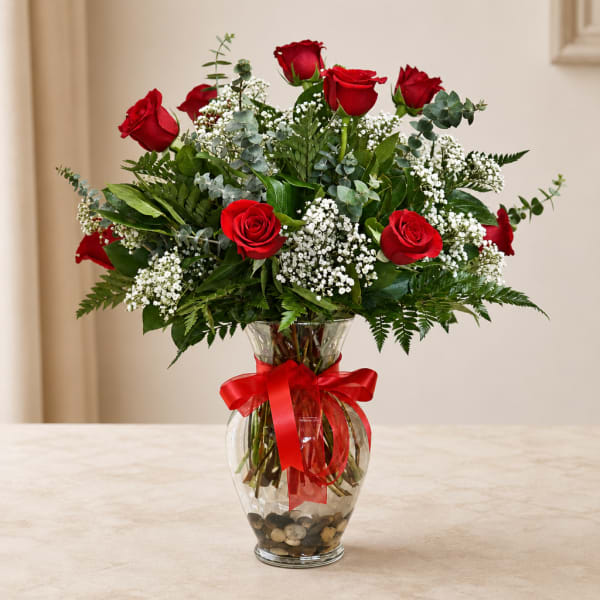 Red roses in a clear glass vase with a red ribbon