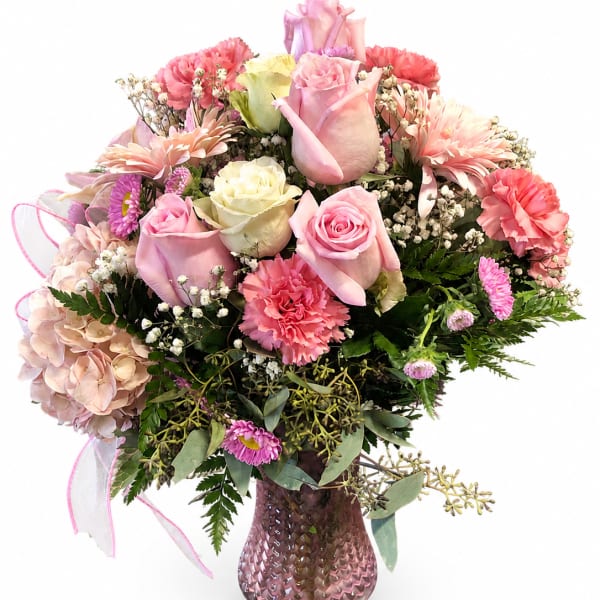 Pink and cream rose bouquet with carnations in a pink vase