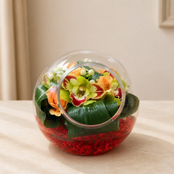 Round glass vase with orange and green flowers and red filler