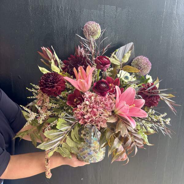 Bouquet of pink lilies, burgundy blooms, and a mosaic vase
