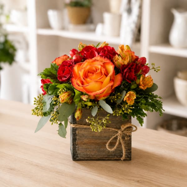 Orange and red rose arrangement in a rustic wooden box