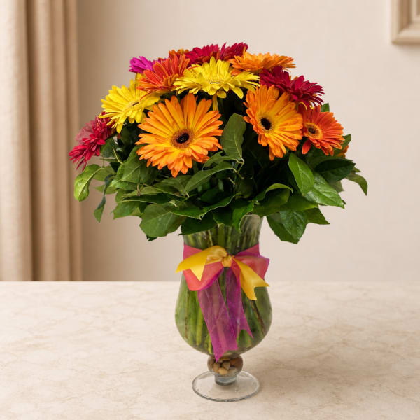Colorful gerbera daisy bouquet in a glass vase with ribbon