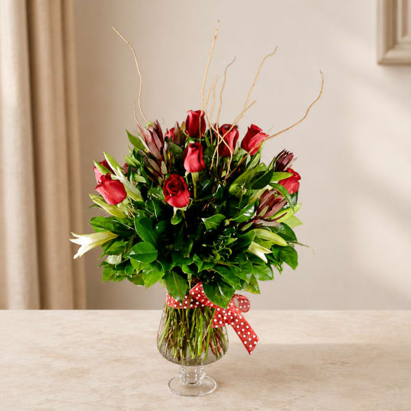 Red roses in a clear glass vase with a red polka-dot ribbon